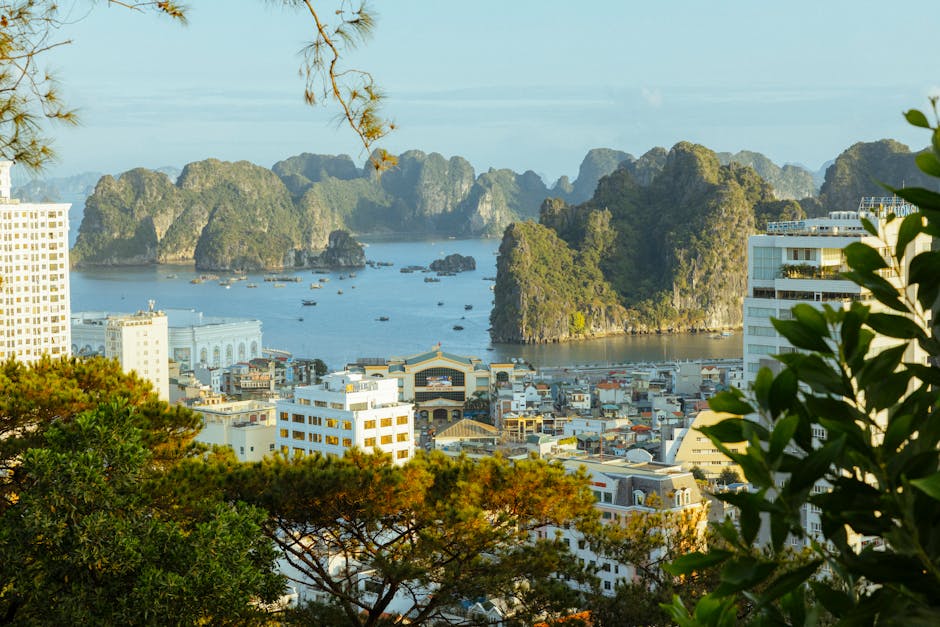 A panoramic view of Ha Long Bay with limestone karsts and urban cityscape, vibrant during the day.