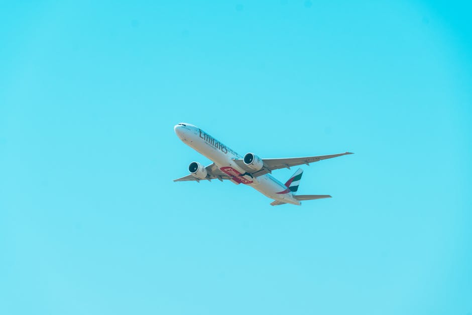An Emirates airline passenger jet flying high against a clear blue sky, showcasing aviation and travel.